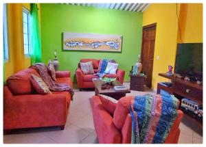 a living room with red couches and a flat screen tv at Villa Monos y Momotos in Los Altos de Cerro Azul