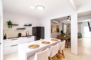 a white kitchen with a table and chairs and a dining room at Casa Marilina Aguadilla w/ Pool in Aguadilla