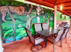 une table et des chaises devant une fresque d'un léopard dans l'établissement Villa Monos y Momotos, à Los Altos de Cerro Azul