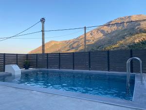 a swimming pool with a fence and mountains in the background at Villa Foteini in Yerakárion