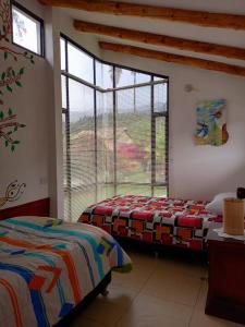 1 dormitorio con 2 camas y ventana grande en El Nido de Paso, en Tibasosa