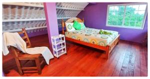 - une chambre avec un lit, une chaise et une fenêtre dans l'établissement Villa Monos y Momotos, à Los Altos de Cerro Azul