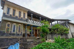 a house with a stone staircase in front of it at Hotel Kampoeng Drini RedPartner in Brono