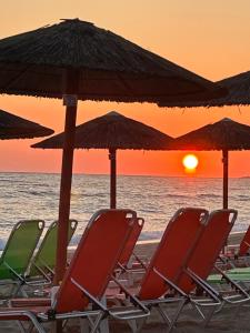 a group of chairs and umbrellas on the beach at sunset at Dream House in Preveza