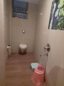 a bathroom with a toilet and a pink stool at Hotel Krishna Sai Kutir in Shirdi