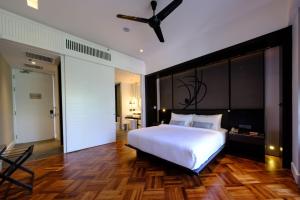 a bedroom with a large white bed with a ceiling fan at Lone Pine, Penang, a Tribute Portfolio Resort in Batu Ferringhi
