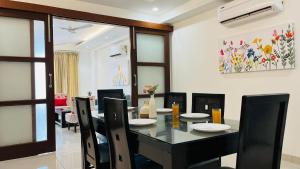 a dining room with a black table and chairs at BluO 3BHK Golf Course Road - Balcony, Lift, Terrace in Gurgaon