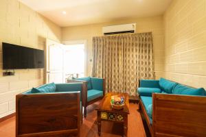 uma sala de estar com sofás azuis e uma mesa em Ibex River Resort, Pollachi em Coimbatore