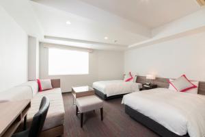ein Hotelzimmer mit 2 Betten, einem Tisch und Stühlen in der Unterkunft Tokyu Stay Gotanda in Tokio