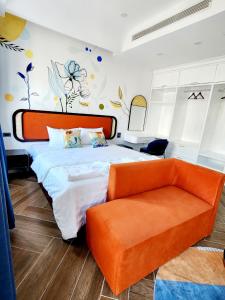 a bedroom with a bed and a orange couch at LITTLE PHU QUOC STUDIO in Phu Quoc