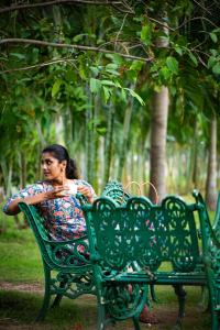 a woman sitting on a green bench in a park at Ibex River Resort, Pollachi in Coimbatore