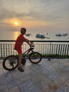 a young boy holding a bike in front of the ocean at LITTLE PHU QUOC STUDIO in Phu Quoc
