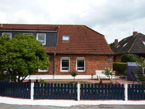 una casa de ladrillo rojo con una valla azul en Ferienwohnung Seestern, en Wangerland