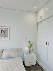 um quarto branco com uma cama e um armário branco em Lucy Homestay - Hoàng Huy Grand Tower em An Lạc