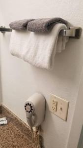a bathroom with towels and a hair dryer on a wall at OSU 2 Queen Beds Hotel Room 133 Hot Tub Booking in Stillwater
