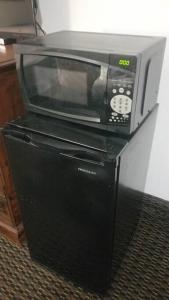 a microwave oven sitting on top of a refrigerator at OSU 2 Queen Beds Hotel Room 133 Hot Tub Booking in Stillwater