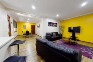 a living room with a leather couch and a tv at Benalla Apartments in Benalla