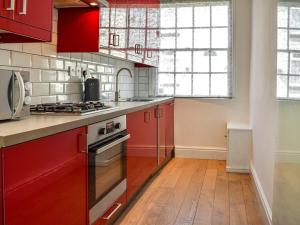 a kitchen with red cabinets and a stove top oven at Waterloo Sunset in Bootle