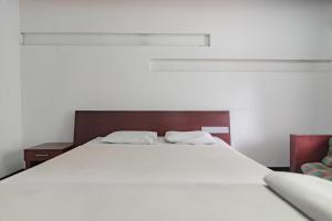 a large white bed with two white pillows on it at Istana Hotel Bandung Mitra RedDoorz in Bandung