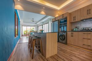 a kitchen with wooden cabinets and a bar with stools at Maison D'Aaryan in Anse aux Pins