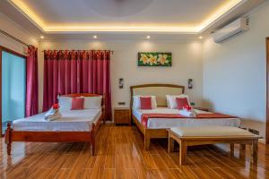 2 camas en una habitación con cortinas rojas en Maison D'Aaryan, en Anse aux Pins