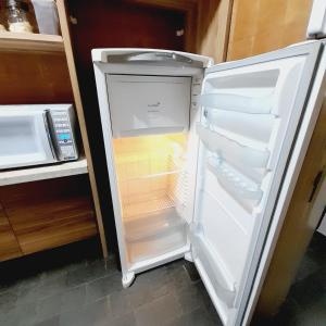 um frigorífico vazio com a porta aberta numa cozinha em APTO - 1,3 km da AFONSO PENA - 3 quartos com ar condicionado em Campo Grande
