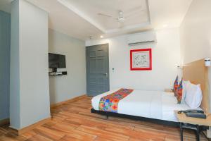 a bedroom with a bed and a desk and a tv at FabExpress PP Residency in New Delhi