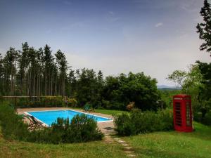 a red phone booth next to a swimming pool at Cottage La Stefania near Anghiari in beautiful setting in Misciano