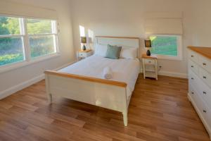 a bedroom with a large white bed and two windows at Baileys Cottage in Adamstown