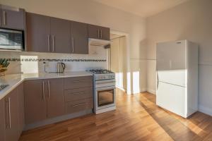 a kitchen with a stove and a refrigerator at Baileys Cottage in Adamstown +4 photos
