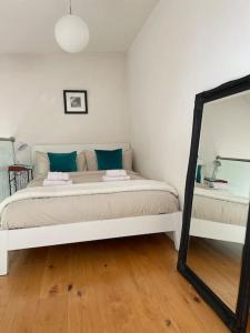 - un lit blanc dans une chambre avec un miroir dans l'établissement Shoreditch Loft, à Londres
