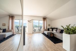 ein Wohnzimmer mit weißen Möbeln und großen Fenstern in der Unterkunft Villa Maria Boutique Apartment St Pauls in Appiano sulla Strada del Vino