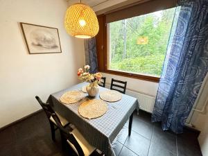 a dining room table with a vase of flowers and a window at Spacious and modern apartment in Mikkeli