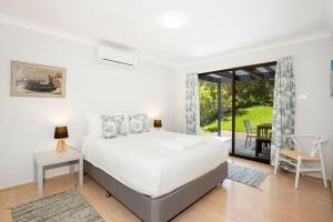 Un dormitorio con una cama y una ventana grande. en Mariners Retreat Jervis Bay, en Vincentia