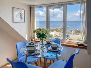 a dining room with a table and blue chairs and a window at Cross Tides in Hilton of Cadboll