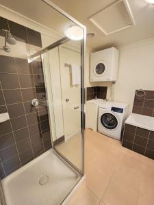 a bathroom with a shower and a washing machine at Oceanic on Thompson Apartments in Cowes