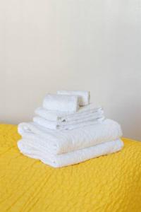 une pile de serviettes blanches assises sur une table jaune dans l'établissement Modern Cottage near many conveniences, à Oakland