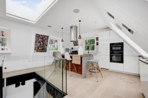 a kitchen with white cabinets and a dining room with a table at Luxury 3 Bed House by Hyde Park, Bayswater in London