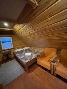 Habitación con cama y silla en una cabaña de madera en Gintaro pirtelė, en Lazdijai