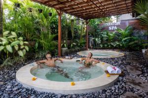 two men sitting in a hot tub in a garden at Hideaway Villas Candy-Ubud by Kanaan Hospitality in Ubud
