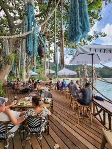a group of people sitting at tables on a wooden deck at Haadson Resort & Koh Raham in Haad Son