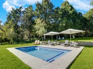 a swimming pool with chairs and umbrellas in a yard at Amberhall Guesthouse in Johannesburg