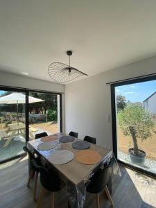 une table de salle à manger avec des chaises et une grande fenêtre dans l'établissement Maison neuve à 2 pas des plus belles plages de Douarnenez - Classé Meublé de Tourisme 3 étoiles, à Kerlaz
