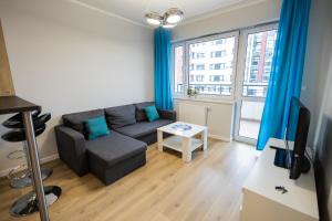 uma sala de estar com um sofá e uma televisão em Apartament Strefa Czasu em Toruń