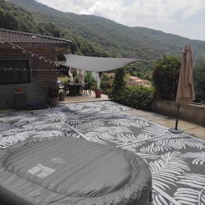 un patio de azulejos con piscina y sombrilla en A Casa Vadiiolina - Villa Radriimas d'exception en Sollacaro