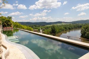 a swimming pool on the side of a river at Sarrasins Bed and Breakfast in Beynac-et-Cazenac