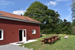 a red building with a picnic table next to it at Gîte de Montagne "Les Ecorces" in La Bresse