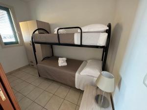 mały pokój z 3 łóżkami piętrowymi i lampką w obiekcie Appartamenti Le 2M w mieście San Pietro in Bevagna