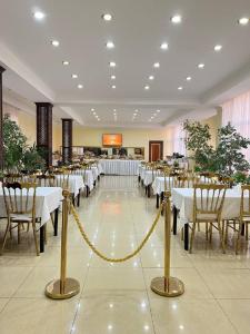 una sala banchetti con tavoli e sedie bianchi e una corda gialla di Rangrez Hotel a Bukhara