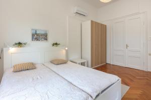 a white bedroom with a large bed with two pillows at Splendid View apartment Opatija in Opatija